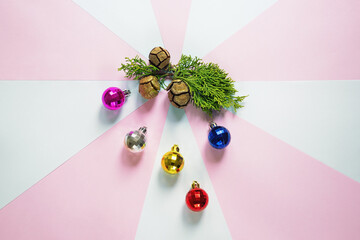Colorful Christmas balls and green cypress tree branch with cones on paper background. Flat lay, free space for text