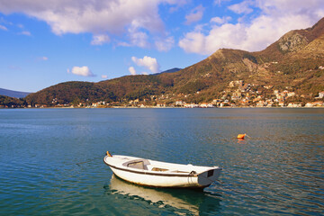 Fototapeta na wymiar Beautiful Mediterranean landscape on sunny winter day. Montenegro, Adriatic Sea. View of Kotor Bay and fishing boat on water. Kamenary town in distance