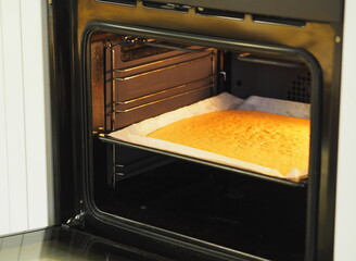 A biscuit layer was baked in the kitchen oven for making a pastry roll.Home cooking.