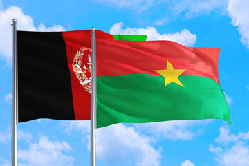 Burkina Faso and Afghanistan national flag waving in the wind on a deep blue sky together. High quality fabric. International relations concept.
