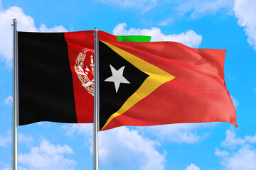 Fototapeta na wymiar East Timor and Afghanistan national flag waving in the wind on a deep blue sky together. High quality fabric. International relations concept.