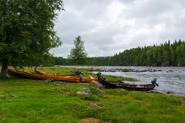 Fototapeta na wymiar Boats used for fishing in the rapids with rapid and a cloudy sky in background
