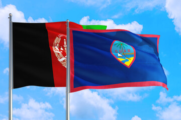 Guam and Afghanistan national flag waving in the wind on a deep blue sky together. High quality fabric. International relations concept.