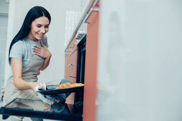 Fototapeta na wymiar Pleased lady admiring her homemade croissants in the kitchen