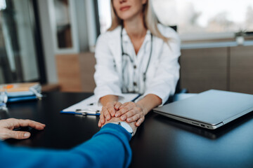 Beautiful female doctor and male patient talking while sitting at the table in the doctor's office....