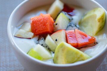 Fresh fruit salad with yogurt in white bowl on clean table background, Healthy Eating,Food for beautiful skin and weight control popular among women who love health, Selective focus.