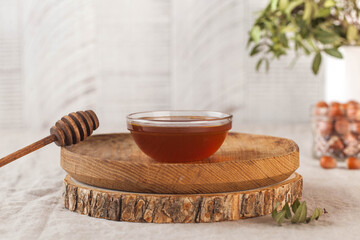 Brown honey in a glass bowl on a rustic wooden plate. Copy space.