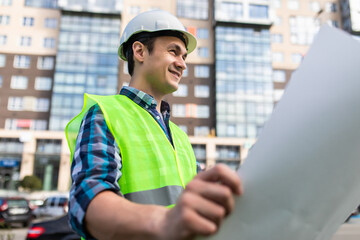 Fototapeta na wymiar portrait of handsome young man with blueprint architect on a building industry construction site