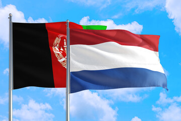Netherlands and Afghanistan national flag waving in the wind on a deep blue sky together. High quality fabric. International relations concept.