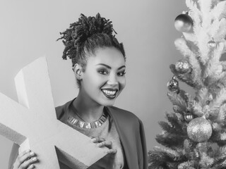 cheerful afro american woman with pink letter X in her hands on the christmas tree background. Christmas, new year, happiness, holidays concept