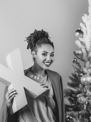 cheerful afro american woman with pink letter X in her hands on the christmas tree background. Christmas, new year, happiness, holidays concept