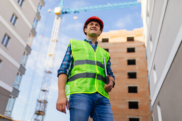 Male architects holding on laptop walking at construction site