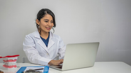 Young Hispanic dental therapist talking on a phone in her office