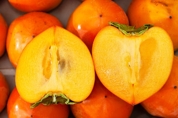 Fresh juicy ripe organic persimmons in a box with cut in half one.