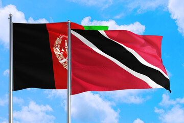Trinidad And Tobago and Afghanistan national flag waving in the wind on a deep blue sky together. High quality fabric. International relations concept.