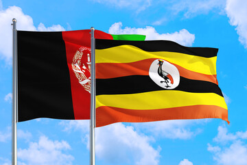 Uganda and Afghanistan national flag waving in the wind on a deep blue sky together. High quality fabric. International relations concept.