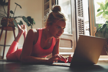 Young woman doing stretching exercise in front of laptop at home.