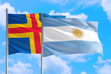 Argentina and Aland Islands national flag waving in the windy deep blue sky. Diplomacy and...