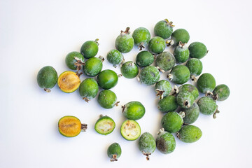 Large fleshy juicy Feijoa berries. Ripe dark green with sepals. A scattering of fruit on a light table. Whole and cut slices.