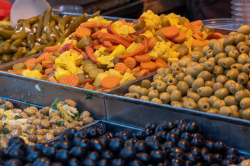 Pickles (olives, carrot and yellow cauliflower) on a white plate and a blue table - close up