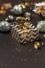 Christmas festive holiday card. Gold and silver decorations, mirror disco balls, gift box on  dark black background.
