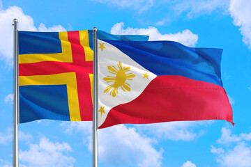 Philippines and Aland Islands national flag waving in the windy deep blue sky. Diplomacy and international relations concept.