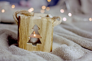 Christmas winter background. Wooden decorative lantern in the form of a cube with a carved herringbone on the bedspread close-up, the concept of a cozy christmas, home warmth, hygge atmosphere