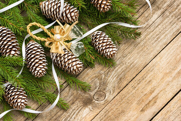 A Christmas concept of fir branches and cones is assembled on a wooden background.