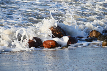 Blue waves of the sea, hitting the stones, turn into white foam. Freezing for a moment, it turns...