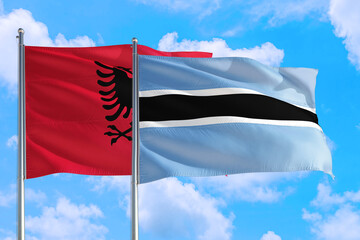 Fototapeta na wymiar Botswana and Albania national flag waving in the windy deep blue sky. Diplomacy and international relations concept.