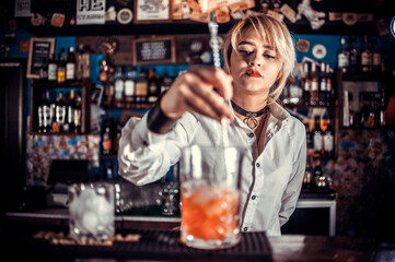 Girl bartender mixes a cocktail in the taproom