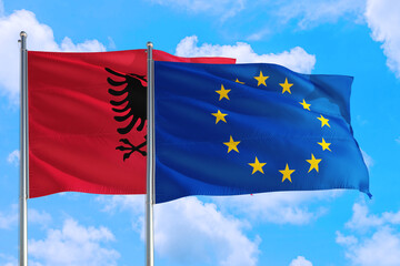 European Union and Albania national flag waving in the windy deep blue sky. Diplomacy and international relations concept.