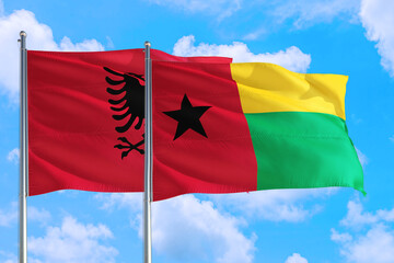 Guinea and Albania national flag waving in the windy deep blue sky. Diplomacy and international...