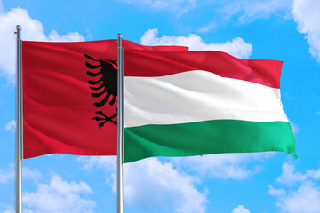 Hungary and Albania national flag waving in the windy deep blue sky. Diplomacy and international relations concept.