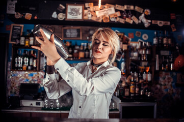 Focused woman bartender intensely finishes his creation in pub