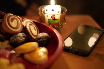 Black cellphone lying offline on a wooden table near candlelight on christmas eve.