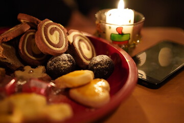 Black cellphone lying offline on a wooden table near candlelight on christmas eve.