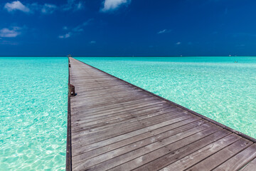 Fototapeta na wymiar Jetty over atoll and a tropical resort island in Maldives