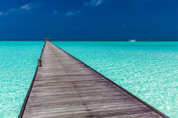 Naklejka premium Jetty over atoll and a tropical resort island in Maldives