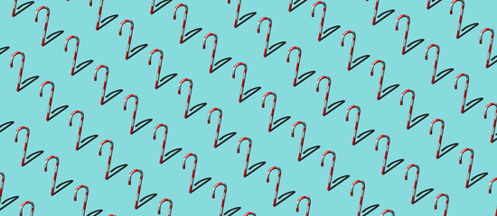 3D illustration/ rendering of pattern of red and white candy cane sticks and lollipops on light pastel blue background. Flat lay. Copy space. Christmas theme card or banner or background