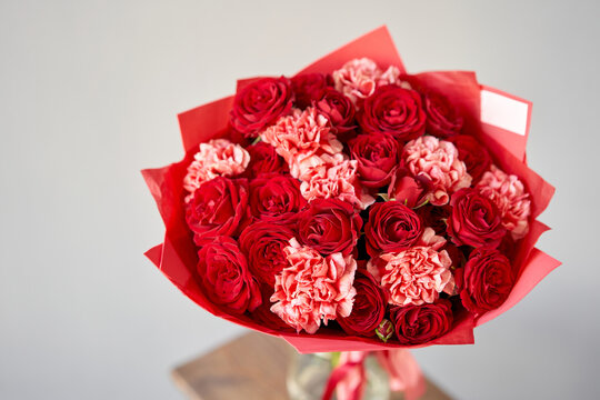 Red flowers. Autumn bouquet of mixed flowers in glass vase on wooden table. The work of the florist at a flower shop. Fresh cut flower.