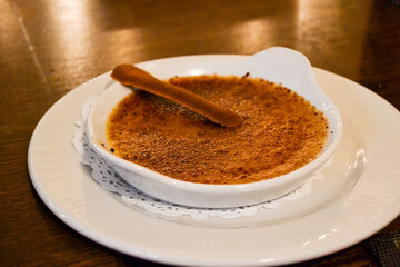Bowl of Creme Brulee on a wooden table. Delicious caramelized dessert background. Traditional famous French burnt cream dessert