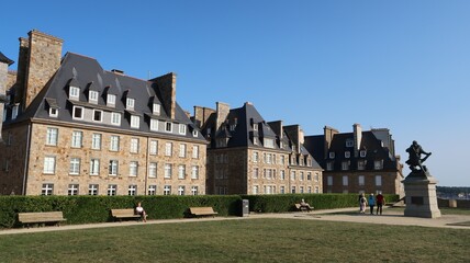 Bastion de la Hollande, place bordée d’immeubles, avec une pelouse, sur les remparts de la ville de Saint-Malo intra-muros, en Bretagne (France)
