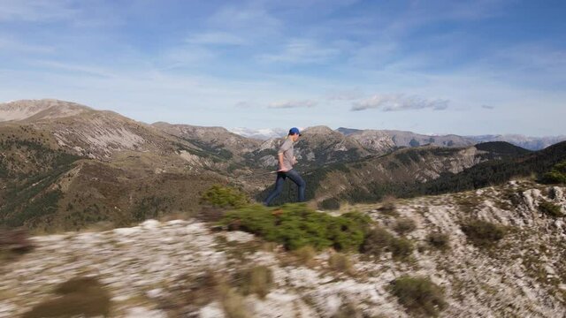 une homme court avec des b&acirc;tons le long d'une cr&ecirc;t montagneuse