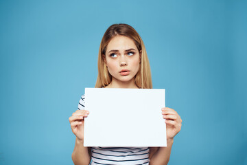 Naklejka premium Emotional woman holding a sheet of paper in her hands lifestyle close-up blue background Copy Space