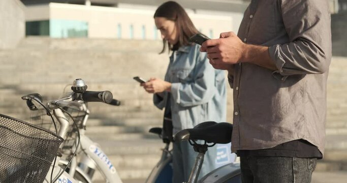 Man and woman text messaging using mobile phones about to ride an electric scooter