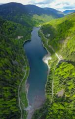 Aerial drone view with Petrimanu hydroelectric Lake in its full length and its arched dam. Springtime in Latorita Massif.