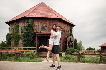 Fototapeta na wymiar Couple in love walks near a large wooden mill on summer day. man and woman are having fun outdoors.