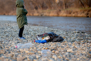 Save environment concept, a little boy collecting garbage and plastic bottles on the beach to dumped into the trash