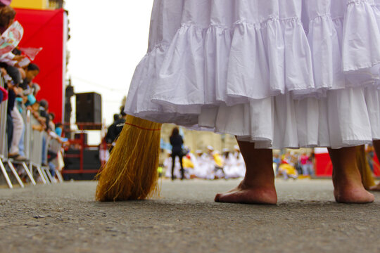 Peruvian woman's feet on a pasacalle in the city of Lima, 2014.

feet of a woman with dress broom and people

